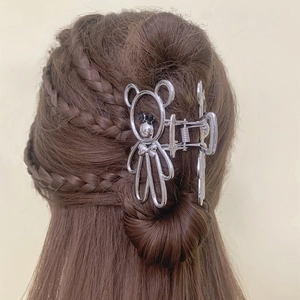 Détail d'une pince à cheveux en métal argenté en forme d'ours avec perles noires
