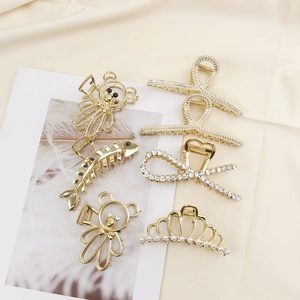 Detailed close-up of six gold alloy hair claws with pearls and rhinestones on beige fabric