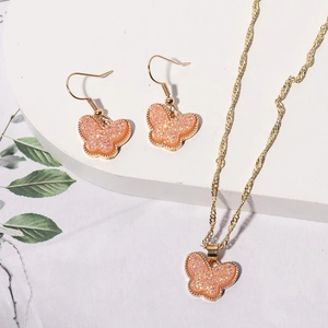 Macro detail of butterfly jewelry set with pink glitter resin and golden frames