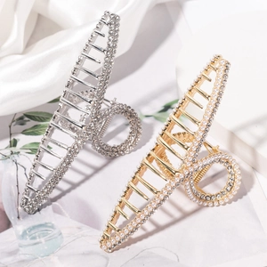 Elegant gold and silver hair claw clips with pearls and rhinestones on silk background