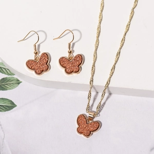 Elegant gold butterfly jewelry set including matching earrings and a necklace on white stand