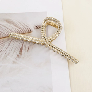 Elegant gold metal hair claw clip with inlaid white pearls on decorative card