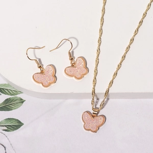 Detailed view of pink glitter butterfly necklace and earrings set with gold twisted chains