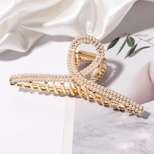 Detailed macro view of golden alloy hair claw clip with white pearls on silk background