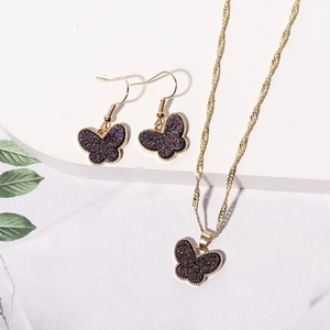 Detailed view of dark purple butterfly jewelry set on a white marble display stand