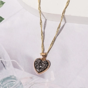 Detailaufnahme einer goldenen Herzanhänger-Halskette mit dunklem Steininlay und Kette