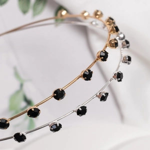 Close-up of thin metal headbands with black rhinestones in gold and silver finish