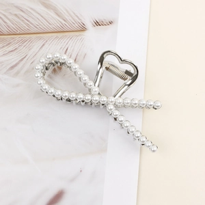 Detail of silver ribbon bow hair claw clip with elegant pearls and heart design
