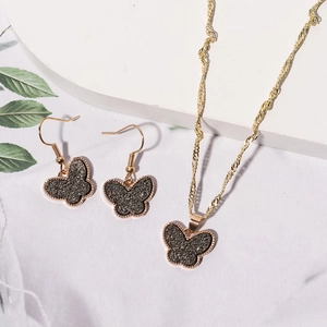Detail of elegant gold butterfly jewelry set featuring dark grey matte finish textures