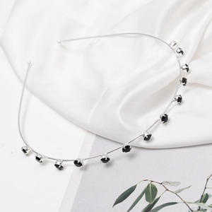 Detail of slim silver metal headband featuring claw-set black round rhinestones on silk