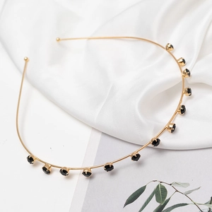 Detail of elegant gold alloy headband featuring black rhinestones on white silk