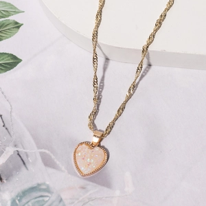 Detailaufnahme des rosa Herzanhängers mit goldenem Perlenrand an einer Wasserwellenkette