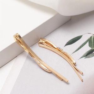 Elegante goldene Schleifen-Haarspangen mit Perlen und Strass auf minimalem Hintergrund