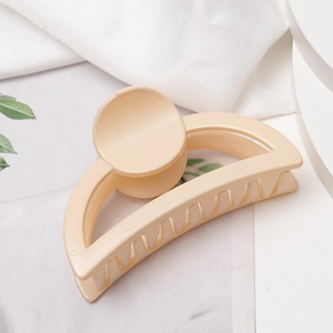 Vue détaillée d'une pince à cheveux beige crème sur tissu blanc avec décor végétal