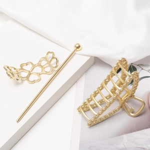 Eleganter Haarklammer und Haarnadel-Set aus goldfarbenem Metall auf weißem Seidenhintergrund