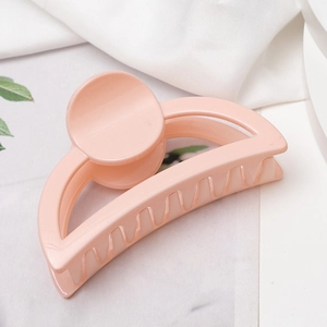 Vue détaillée de la pince à cheveux rose pêche brillante sur un tissu blanc doux