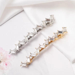 Barrettes élégantes en or et argent avec cristaux sur fond de soie blanche douce