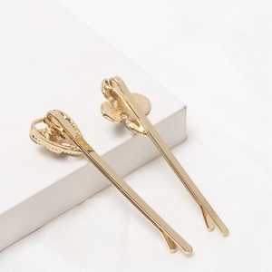 Elegant gold metal hairpins with heart and floral rhinestone charms on white cubes
