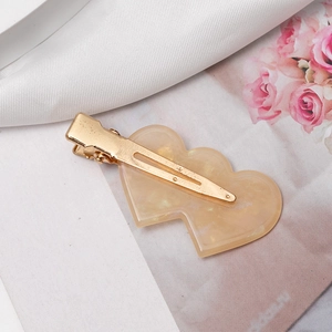 Macro shot of double heart cream acetate hair clip on elegant white silk fabric