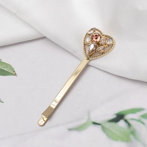 Elegant gold heart hair clip with champagne crystals on soft white silk background