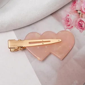 Detail of pink pearlescent resin heart hair clip with gold metal alligator base