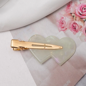Detail of double heart resin hair clip with pearlescent finish and gold metal base