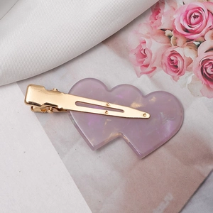 Detail of heart-shaped purple acetate hair clip with golden metal duckbill base