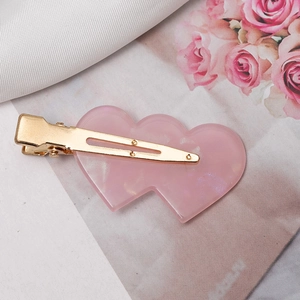 Detail of pink marble resin heart clips on gold metal base with elegant floral accents