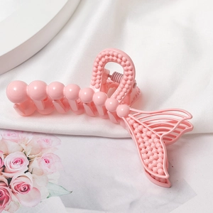Détail de la pince à cheveux sirène rose avec perles sur un tissu blanc texturé
