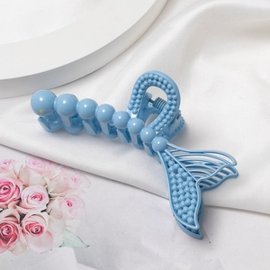 Détail de la pince à cheveux queue de sirène bleu clair avec texture perlée sur de la soie