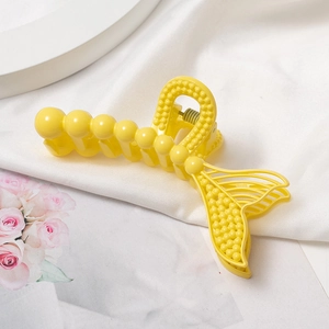 Gros plan sur une pince à cheveux jaune en forme de queue de poisson texturée de perles