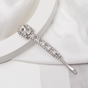 Detail of silver hair clip with clear rhinestones and large emerald-cut crystals on silk