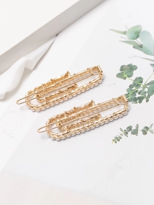 Detail of two-piece French style gold metal hair clips with white pearls set in a frame
