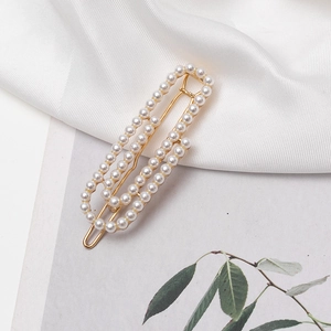 Detailed close-up of a French style pearl hair clip on an elegant white silk background
