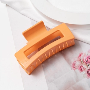 Détail d'une pince à cheveux rectangulaire en résine orange vif au design ajouré