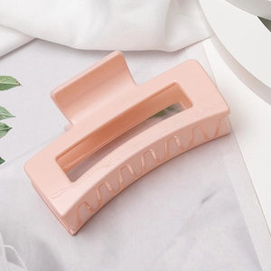 Détail d'une pince à cheveux rectangulaire rose avec finition brillante sur tissu