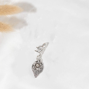 Macro detail of vintage silver dreadlock spiral clip with leaf and flower pendant