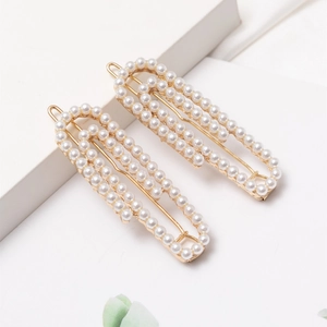 Pair of elegant French-style pearl paperclip hairpins on minimalist white steps