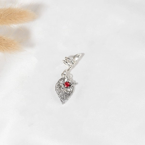 Detail of silver dreadlock hair clip featuring a spiral coil and a ruby red leaf pendant