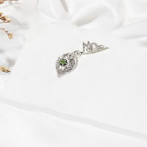 Detail of vintage silver spiral dreadlock clip with leaf pendant and green crystal