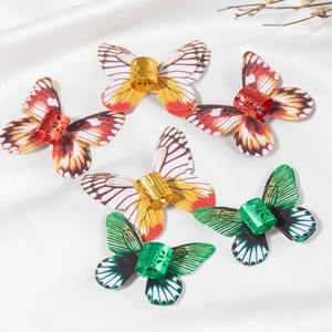 Detailed view of butterfly dreadlock rings in red, yellow, and green on silk fabric