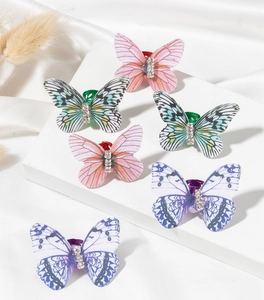 Detail of six butterfly hair clips with rhinestone accents on elegant white fabric