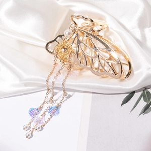 Élégante pince à cheveux papillon dorée avec de longs glands en perles sur satin blanc