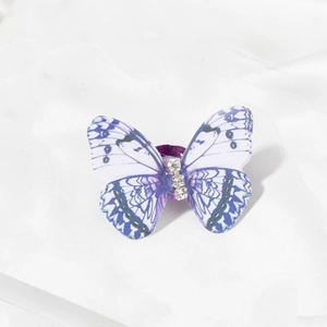 Detail of a purple and white butterfly hair clip with rhinestones on silk background