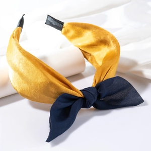 Detail eines gelben Satin-Haarreifs mit dunkelblauer Schleife auf weißem Ständer