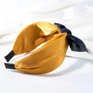 Detail eines senfgelben Satin-Haarreifs mit dunkelblauem geknotetem Schleifendekor