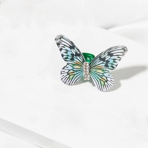 Detail shot of a butterfly hair charm with green wings and three bright inlaid diamonds