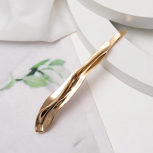 Elegant gold wavy metal hair clip with irregular liquid texture on a white display