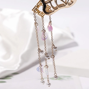 Macro d'une pince à cheveux papillon dorée avec glands en perles et pendentifs