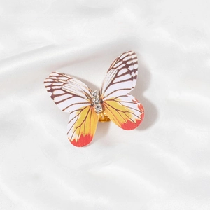 Detail of a butterfly hair charm with orange gradient wings and sparkling rhinestones